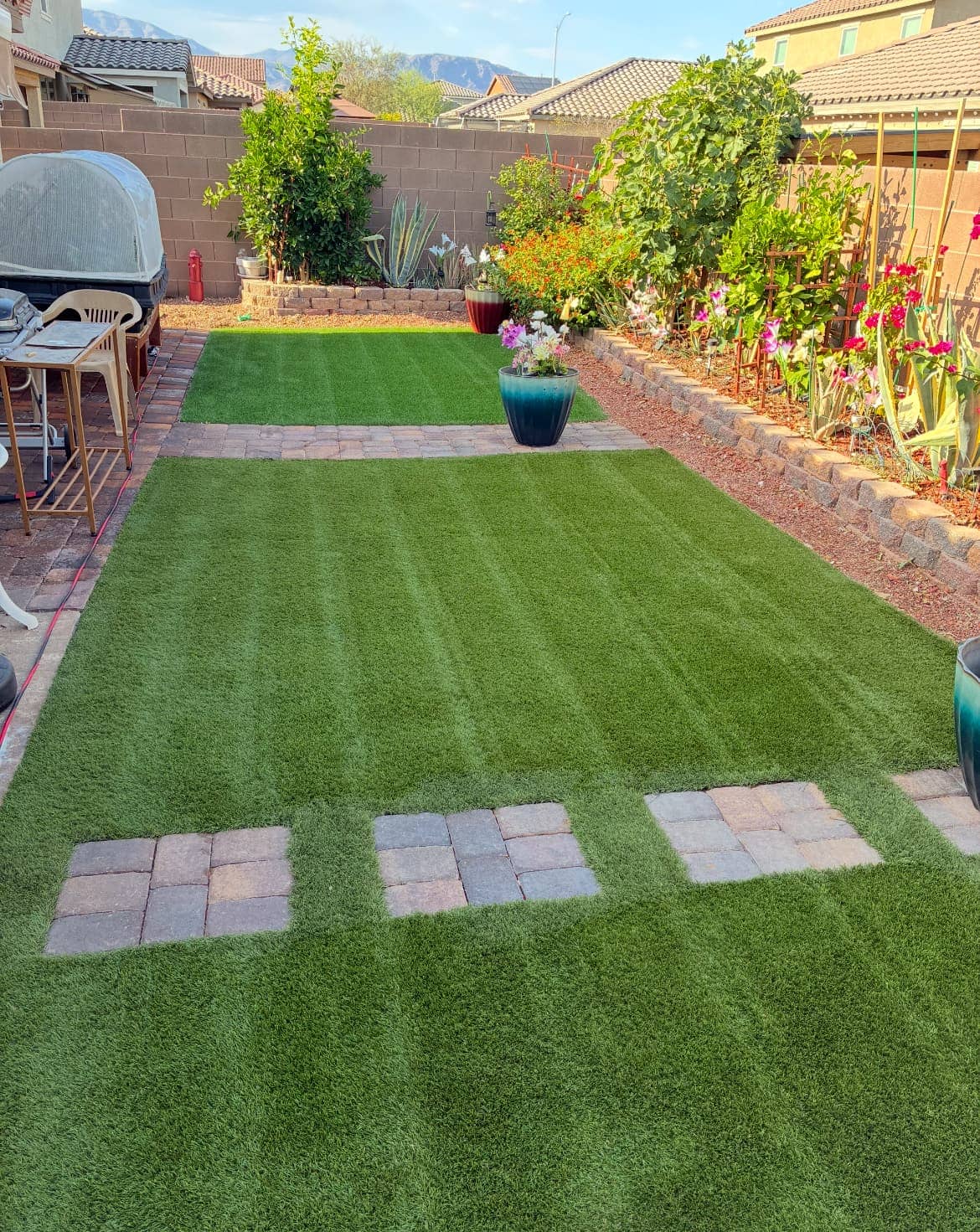 Manicured artificial turf backyard with paver walkways and garden beds
